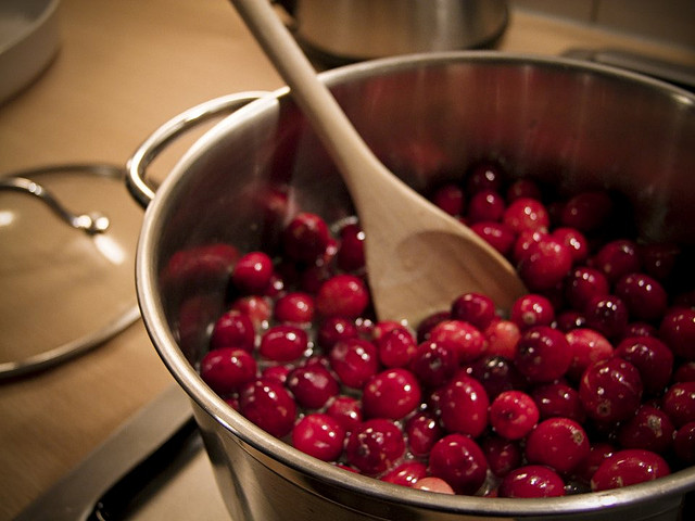 a pot of cranberries with a wooden spoon