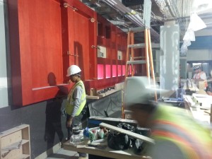 a man in a hard hat and a yellow vest standing next to a red wall