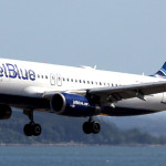 a jet blue airplane flying over water