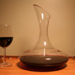 a glass of wine next to a decanter
