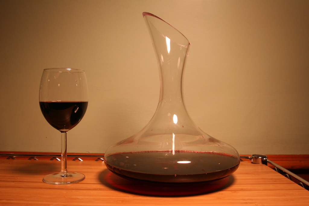 a glass of wine next to a decanter