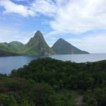 a body of water with trees and mountains with Pitons in the background