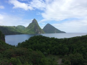 a body of water with trees and mountains with Pitons in the background