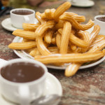 a plate of churros and cups of chocolate
