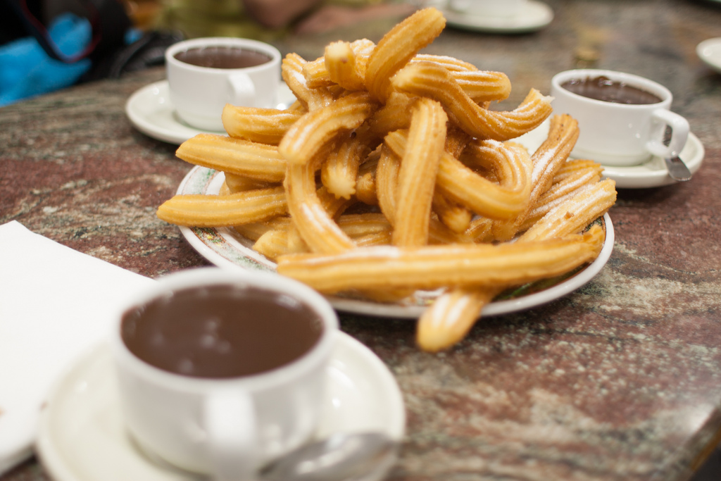 a plate of churros and cups of chocolate
