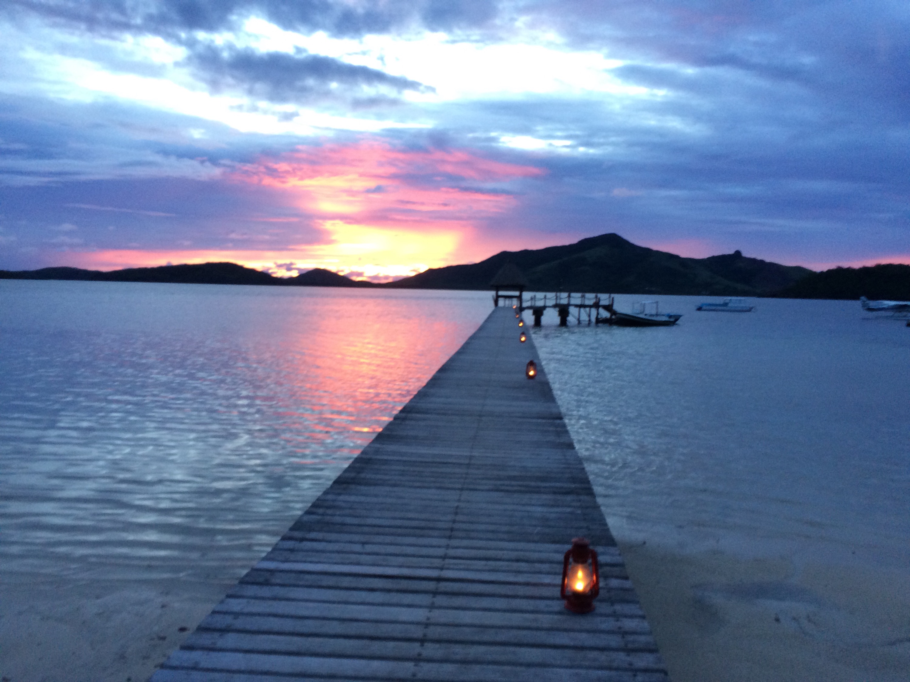 a dock with candles on it and a sunset in the background