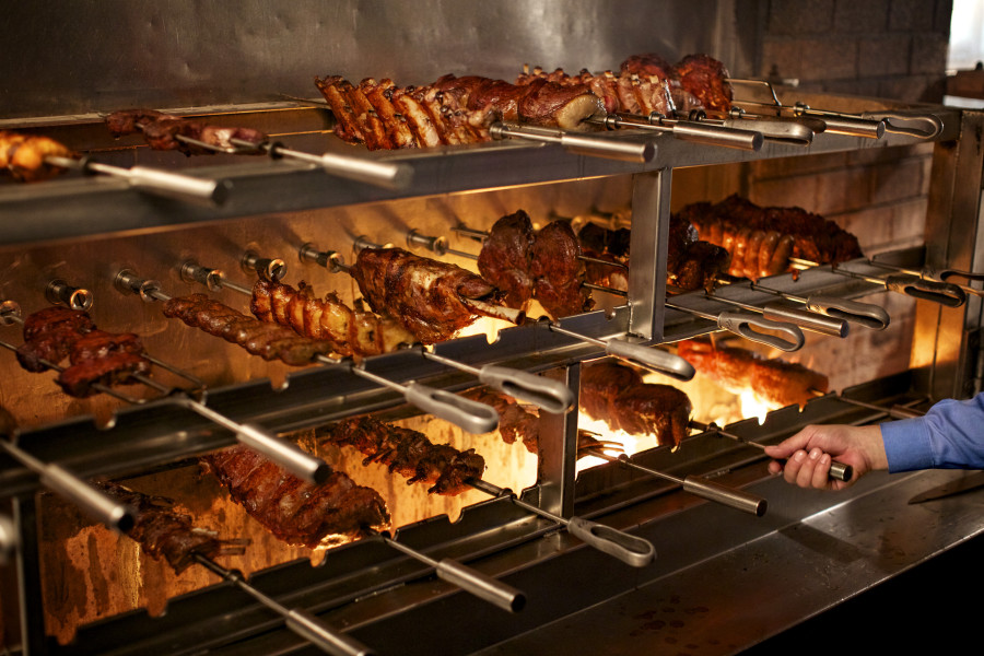 a person standing in front of a large rack of meat