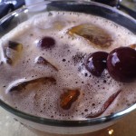 a glass with brown liquid and cherries