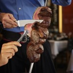 a person cutting meat on a skewer