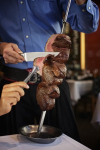 a person cutting meat on a skewer