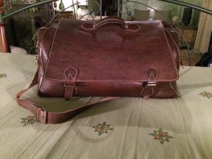 a brown leather bag on a bed