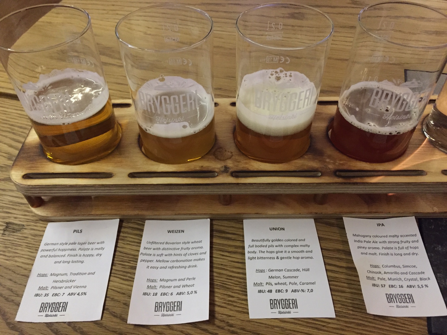 a row of glasses with beer on a wooden tray