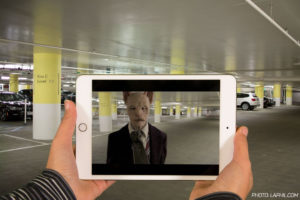 a person taking a picture of a man in a parking garage