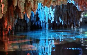 a cave with water and stalactites with Reed Flute Cave in the background